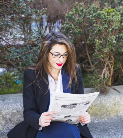 business-woman-reading-newspaper-outside